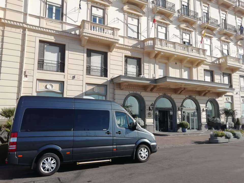 Private transfer vehicles parked in front of a historic hotel on the Amalfi Coast.
