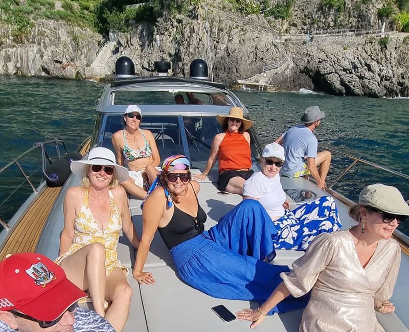 People enjoying outdoor activities on a boat, sailing, kayaking, and snorkeling in the Amalfi Coast.

