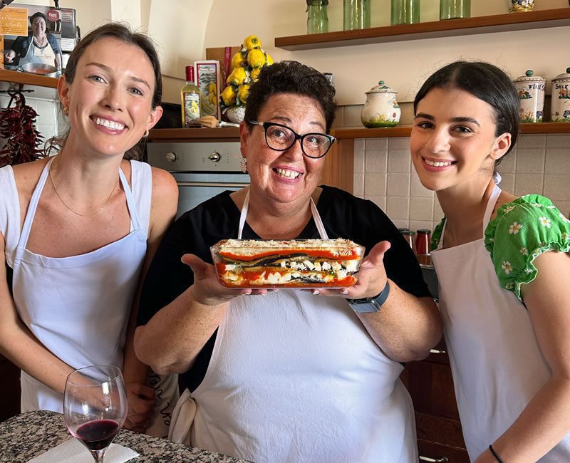 People cooking together and enjoying wine, immersed in a culinary experience on the Amalfi Coast.
